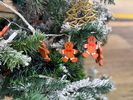 Gingerbread ornaments hanging on frosted Christmas tree branches. Playful holiday decor, winter...