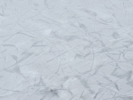 Scratched ice surface on an outdoor skating rink. Winter texture, frozen background, and seasonal sports atmosphere.の写真素材