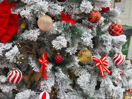 Decorated Christmas tree with red bows and ornaments outdoors. Winter holiday decoration, festive city atmosphere, seasonal celebrationの写真素材