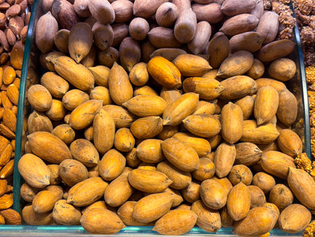 Whole almonds in shells filling a display tray in Istanbul bazaar. Natural nuts, raw ingredients, and nutrient dense food culture expressed through texture, abundance, and agricultural simplicity.の写真素材