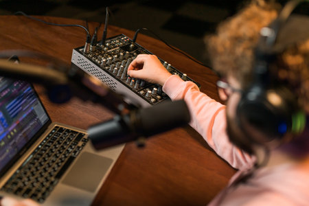 Cheerful young man recording podcast in studio. Confident man with headphones and microphone recording a podcast. Happy guy talking on web radio.の写真素材