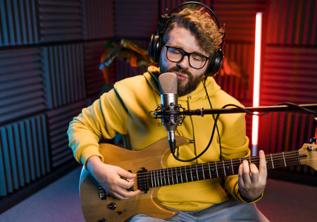 Man vocal artist singing in a recording studio with guitar. Male singer singing a song and playing...