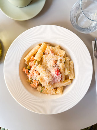 Overhead view of pasta with vegetables and grated cheese on white plate. Culinary scene symbolizing gourmet cuisine, nutrition and lifestyle dining.の写真素材