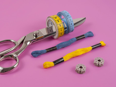 Accessories for sewing thread scissors needle and centimetre on a pink backgroundの写真素材