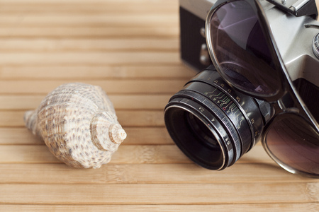 Sunglasses and camera on a wooden background and cockleshellsの写真素材