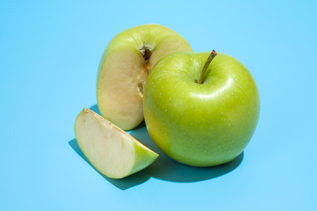 Ripe parts green apple Isolated on a blue background. Healthy eating and dieting conceptの写真素材