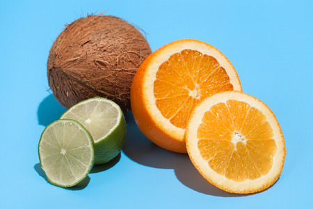 Fresh juicy orange, coconut and green lime isolated on blue background. Concept of Healthy eating and dieting. Travel and holiday conceptの写真素材