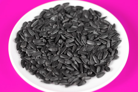 Black sunflower seeds on a pink background. Top view.の写真素材