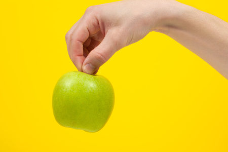 Hand holding organic green delicious apple Isolated on yellow Background. Healthy eating and dieting  conceptの写真素材