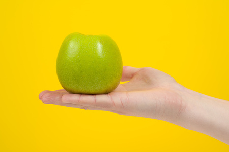 Hand holding organic green delicious apple Isolated on yellow Background. Healthy eating and dieting  conceptの写真素材