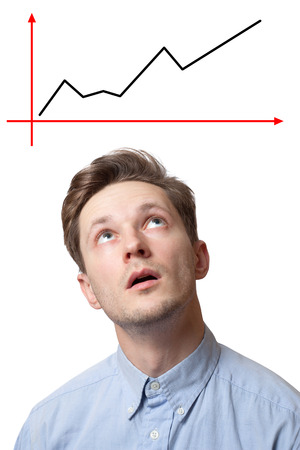 handsome brunette male with pensive expression, dressed in fashionable shirt, tries to remember something, isolated over white background with chart aboveの写真素材