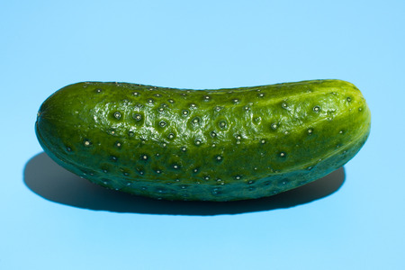 Ripe green cucumber on blue background. Healthy eating and dieting conceptの写真素材