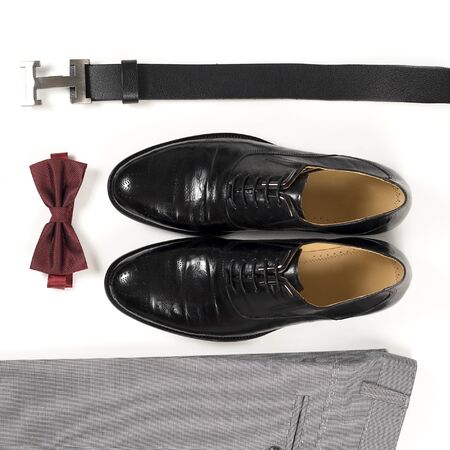 Close up of modern man accessories. Bordeaux bow tie, leather shoes, belt on white  background. Set for formal style of wearing isolated on white background.
の写真素材