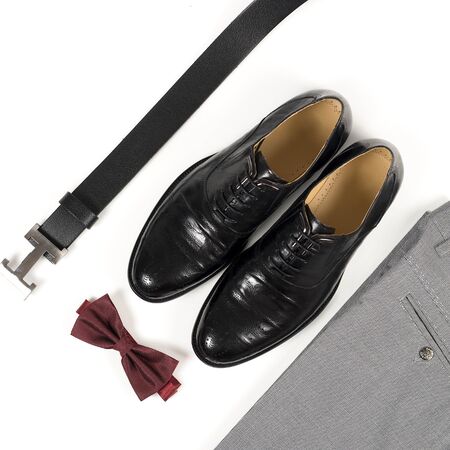Close up of modern man accessories. Bordeaux bow tie, leather shoes, belt on white  background. Set for formal style of wearing isolated on white background.
の写真素材