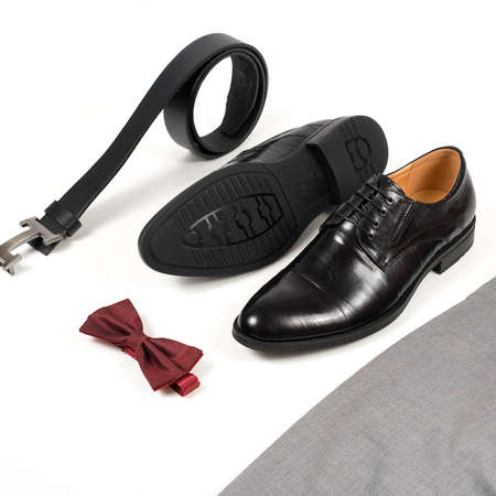 Close up of modern man accessories. Bordeaux bow tie, leather shoes, belt on white  background. Set for formal style of wearing isolated on white background.の写真素材