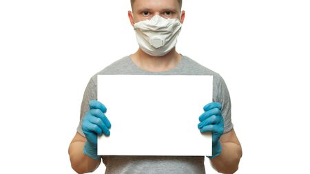 Man in hygienic medical mask and blue gloves holding white poster.の写真素材