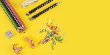 Some colored pencils of different colors and a pencil sharpener and pencil shavings on the yellowの写真素材