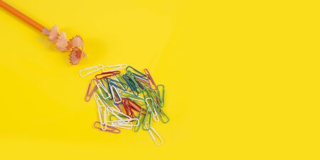 Some colored pencils of different colors and a pencil sharpener and pencil shavings on the yellowの写真素材