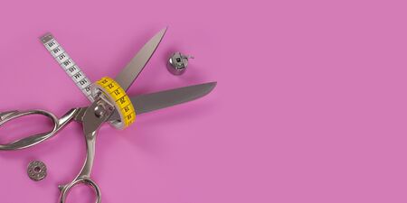 Accessories for sewing thread scissors needle and centimetre on a pink background の写真素材