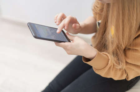 Mockup image of woman's hands holding black mobile phone with blank screen in officeの写真素材