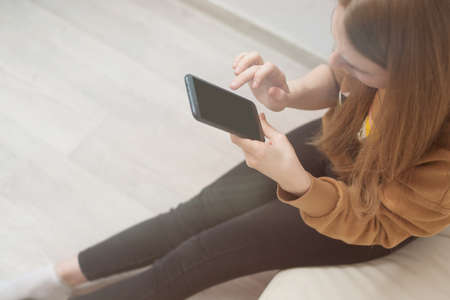 Mockup image of woman's hands holding black mobile phone with blank screen in officeの写真素材