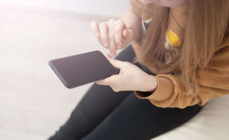 Mockup image of woman's hands holding black mobile phone with blank screen in officeの写真素材