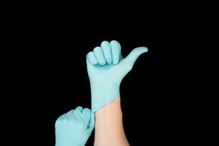 Hand in blue glove isolated on black with thumb up.