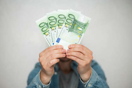 Businessman in blue shirt holds european euro money on white background, closeup. Money, earnings, crediting and finance.の写真素材