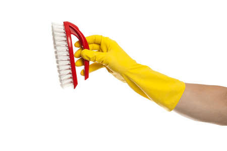 Hand in yellow glove with a red cleaning brush on a white background. Home cleaning conceptの写真素材