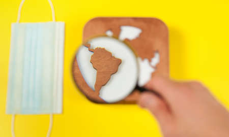 Plane model, face mask, loupe in hand and earth model on a yellow background. Flight impact of...