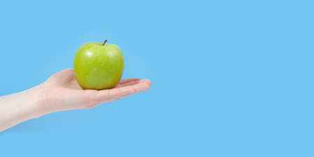Hand holding organic delicious apple Isolated on blue Background. Healthy eating and dieting concept. Copy space. Free space for your textの写真素材