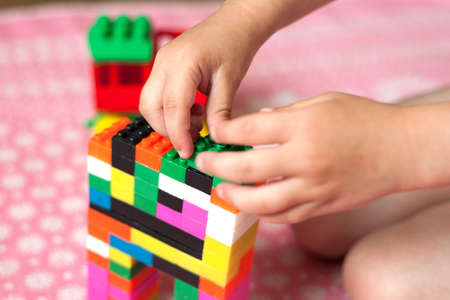Small hands of the child collects the bright plastic colored Designer. Educational toys and Early...
