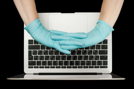 Hands in blue protective gloves typing on laptop keyboard. Top view.  virus concept.の写真素材