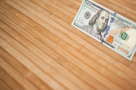 100 Dollars bill and portrait Benjamin Franklin on USA money banknote. Hundred dollar bills on wooden background.の写真素材
