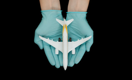 Hand in glove holding model airplanes on black background. Concept traveling. Copy spaceの写真素材