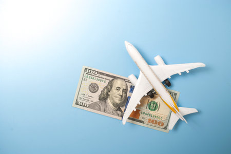 A globe, a toy plane and a 100 dollar bill on blue background. Travel conceptの写真素材