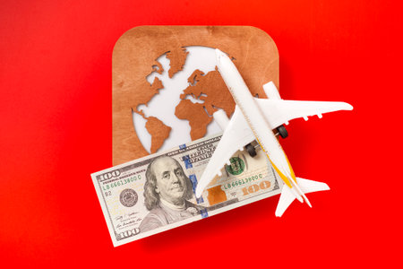 A globe, a toy plane and a 100 dollar bill on red background. Travel conceptの写真素材
