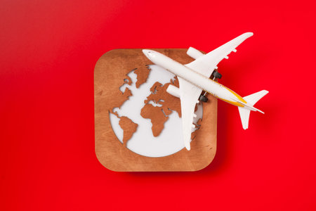 A globe, a toy plane and a 100 dollar bill on red background. Travel conceptの写真素材