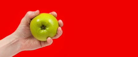 Hand holding tasty organic green delicious apple Isolated on red Backgroundの写真素材