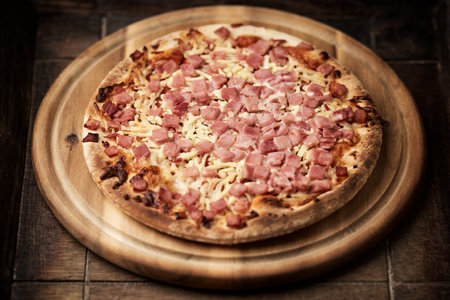 Pizza with ham and cheese on a wooden board. Toned.の写真素材