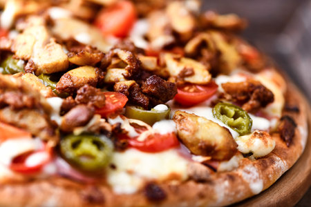 Pizza with meat, cheese and vegetables on a wooden background.の写真素材