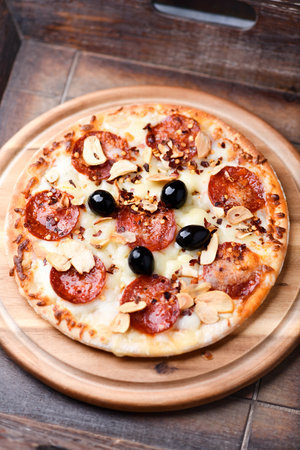 Pizza with salami, cheese and olives on wooden backgroundの写真素材