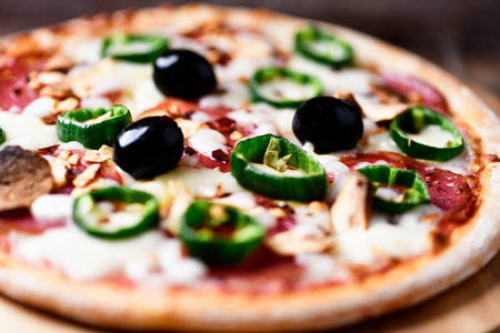 Pizza with cheese and green olives on wooden backgroundの写真素材