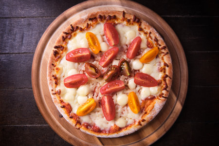 Pizza with mozzarella, tomatoes and basil on a wooden tableの写真素材
