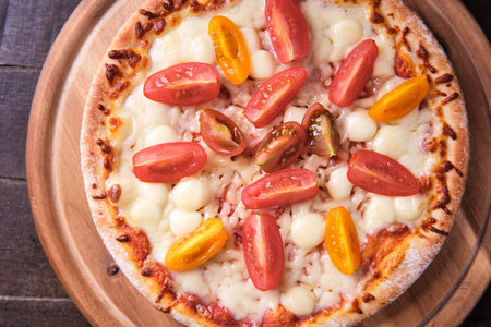 Pizza with mozzarella, tomatoes and basil on wooden backgroundの写真素材