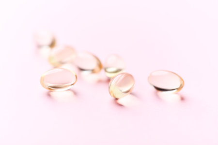 Vitamin D and Omega 3 fish oil capsules on pink background.の写真素材