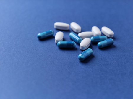 Blue and white pills on a blue background. Focus on foreground, soft bokeh.の写真素材