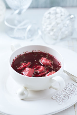 Bowl of borscht with dumplings on white background