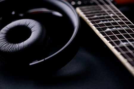Headphones and electric guitar on black background close up. Music conceptの写真素材
