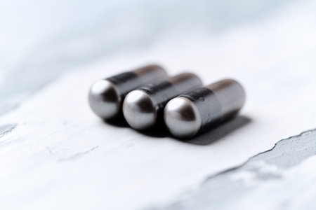 Close up of black pills on white wooden background. Focus on foreground.の写真素材